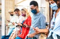 Multiracial friends with face mask using tracking app with mobile smart phones - Young milenial people checking online reservation Royalty Free Stock Photo