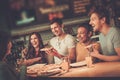 Multiracial friends having fun eating in pizzeria. Royalty Free Stock Photo