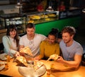 Multiracial friends having fun eating in pizzeria. Royalty Free Stock Photo