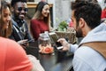 Multiracial friends using mobile phones outdoor at vintage bar restaurant - Focus on center hand holding smartphone Royalty Free Stock Photo