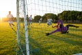 Multiracial goalkeeper defending ball of opponent goal during match against clear sky at sunset Royalty Free Stock Photo