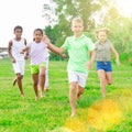 Multiracial group of cheerful tweens running together in city park