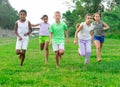 Multiracial group of cheerful tweens running together in city park