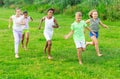 Multiracial group of cheerful tweens running together in city park