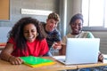 Multiracial group of high school students laughing together in class using laptop to do homework together. Royalty Free Stock Photo