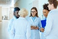 A multiracial group of medical interns in lab coats discussing work Royalty Free Stock Photo