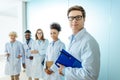 Multiracial group of smiling medical interns in lab coats standing in a row with clipboards Royalty Free Stock Photo