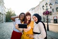 Multiracial group of three young attractive women best friends in colorful clothes, taking selfie in beautiful urban Royalty Free Stock Photo