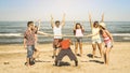 Multiracial happy friends group having fun with limbo at beach