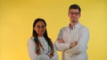 Multiracial male and female doctors nodding their heads to the camera on yellow background.