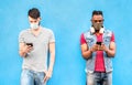 Multiracial male friends with face masks using tracking app with mobile smart phones - Young millenial people watching updates