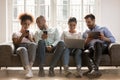 Multiracial friends sitting on sofa with modern electronic devices Royalty Free Stock Photo