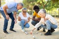 Multiracial mature adult people measuring distance between balls in petanque game outside in a park Royalty Free Stock Photo