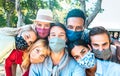 Multiracial milenial friends taking selfie with closed face masks during Covid second wave outbreak - New normal lifestyle concept