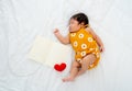 Multiracial newborn baby sleep and lie on bed new notebook with red heart model with day light in concept of happiness sweet dream