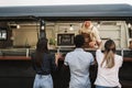 Multiracial people ordering food at counter in food truck outdoor - Focus on take away sign