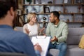 Multiracial quarrel between husband and wife at a session with a psychotherapist. A visit to a family psychologist for a Royalty Free Stock Photo