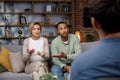 Multiracial quarrel between husband and wife at a session with a psychotherapist. A visit to a family psychologist for a Royalty Free Stock Photo