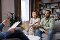 Multiracial quarrel between husband and wife at a session with a psychotherapist. A visit to a family psychologist for a Royalty Free Stock Photo