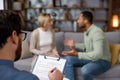 Multiracial quarrel between husband and wife at a session with a psychotherapist. A visit to a family psychologist for a Royalty Free Stock Photo