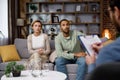 Multiracial quarrel between husband and wife at a session with a psychotherapist. A visit to a family psychologist for a Royalty Free Stock Photo