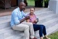 Multiracial senior couple talking while having coffee on steps outside house Royalty Free Stock Photo