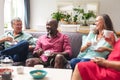 Multiracial senior female and male friends talking while having coffee together at home Royalty Free Stock Photo