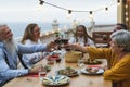Multiracial senior friends having fun dining together and toasting with red wine on house patio dinner Royalty Free Stock Photo