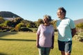 Multiracial senior friends looking away while standing on grassy land against clear sky in yard Royalty Free Stock Photo