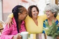 Multiracial senior friends meet and chat at bar outdoor while drinking coffee together at bar restaurant - Focus on center woman Royalty Free Stock Photo