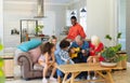 Multiracial senior man playing guitar while sitting with happy multigeneration family on sofa Royalty Free Stock Photo