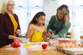 Multiracial senior woman looking at smiling daughter showing recipe over digital pc to granddaughter Royalty Free Stock Photo
