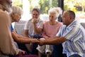 Multiracial seniors holding hands and comforting while sitting with friends in group therapy session Royalty Free Stock Photo