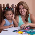 Multiracial small girl and her mother drawing with color pencils