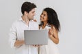 Multiracial smiling couple posing with laptop and credit card