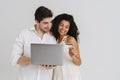 Multiracial smiling couple posing with laptop and credit card