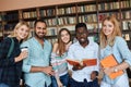 Multiracial students having fun in library while preparing for exams.