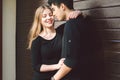 Multiracial stylish couple in black clothes posing on a background of a wooden wall. Turkish guy and caucasian girl date and love