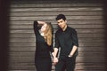 Multiracial stylish couple in black clothes posing on a background of a wooden wall. Turkish guy and caucasian woman date and love Royalty Free Stock Photo