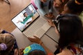 Multiracial teacher and students looking at boy on laptop screen while studying online in classroom Royalty Free Stock Photo