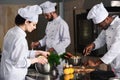Multiracial team of cooks cooking by kitchen stove Royalty Free Stock Photo