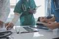 Multiracial team of doctors discussing a patient standing grouped in the foyer looking at a tablet computer, close up view Royalty Free Stock Photo