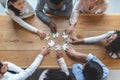 Multiracial team sitting around table, putting together puzzle pieces