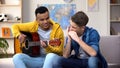 Multiracial teenage friends playing guitar and mouthorgan hobby musician career Royalty Free Stock Photo