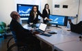 Multiracial trader team making stock market analysis conference inside hedge fund office - Focus on senior man in wheel chair