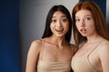 Multiracial two women expressing surprise at camera