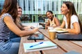 Multiracial university students laughing outdoor in college campus studying and doing homework using laptops. Royalty Free Stock Photo