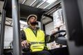 Multiracial warehouse worker driving forklift. Warehouse worker preparing products for shipmennt, delivery, checking Royalty Free Stock Photo