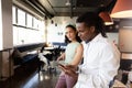 Multiracial young businessman and businesswoman with laptop and smart phone discussing in office Royalty Free Stock Photo