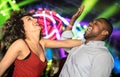 Multiracial young couple dancing at night club with laser light show